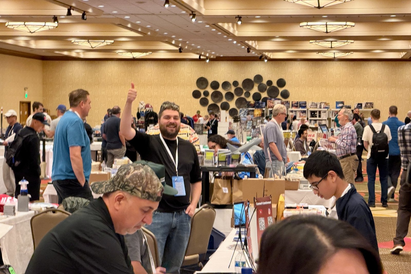 Smiling Aviation Expo exhibitor giving a thumbs-up in the marketplace